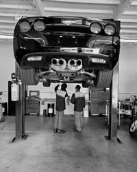 Technicians inspecting a car on a lift